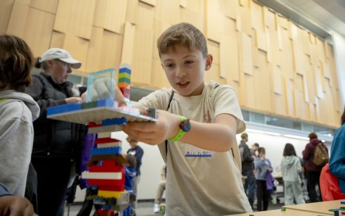A child builds a Lego protection tower on a table at the ETEC atrium.