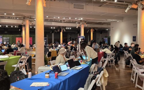  A spacious room filled with numerous people seated at tables, engaged in conversation and activities. 