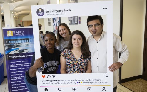 Four students poses together holding a sign read "ualbanygradsch"