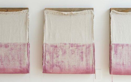 Howard Schwartzberg's work: three wooden frames with half cream and half pink cloth stapled to them hang from a wall.