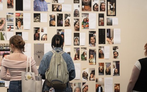 Visitors to the UAlbany Museum observe a series of photos and written works on a wall.