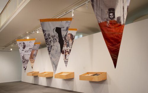Triangular flags hang from the cieling, photographs printed on them.