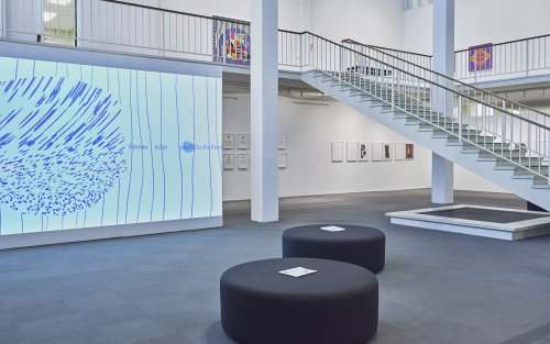 A graphic art piece is projected onto a wall in the UAlbany Museum space.