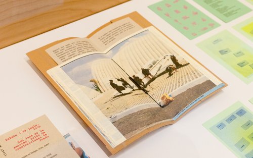 A handmade book sits open on a table, surrounded by an assortment of notes.