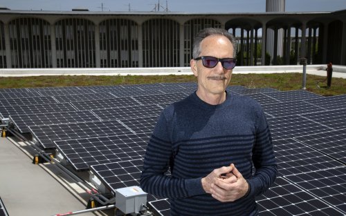 Richard Perez stands with sun glasses on in front of solar panels on top of UAlbany's Campus Center.