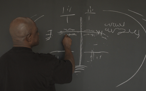 A person draws and writes on a chalkboard.