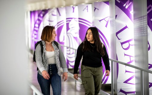 Students walking past UAlbany seal
