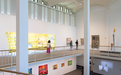 Student walk through and observe the Master of Fine Arts Thesis Exhibition.