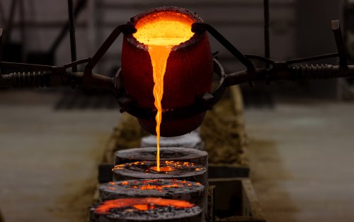 a crucible pours hot molten bronze into several casts during a crucible pour in UAlbany's Boor sculpture studio