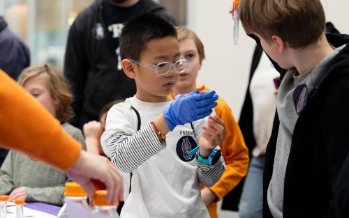 A young student holds up a beaker at STEM and Earth Sciences Family Day.