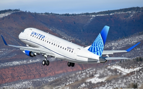 A jet labeled "United Express" flies over mountains.