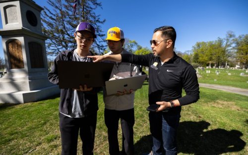 Students Micah Wang and Weiming Lan stand with Associate Professor Rui Li at the site of the Civil War memorial at Albany Rural Cemetery in Menands, N.Y. (Photo by Patrick Dodson)