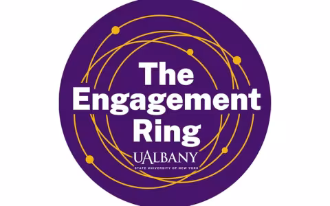 round purple logo with intersecting gold rings and the words "The Engagement Ring UAlbany"