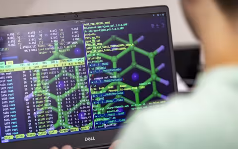A photo taken over the shoulder of someone looking at a computer screen showing a list of complex numbers and complex molecular structures.