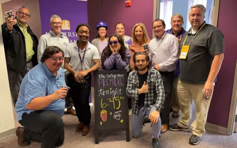 A dozen Communications & Marketing staff members smile and pose for a photo.