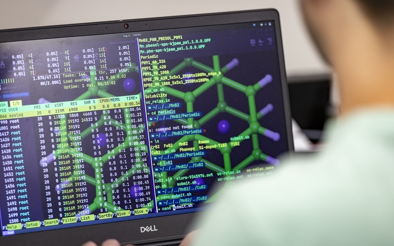 A photo taken over the shoulder of someone looking at a computer screen showing a list of complex numbers and complex molecular structures.