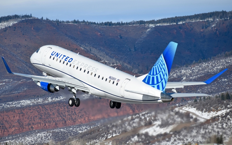A jet labeled "United Express" flies over mountains.