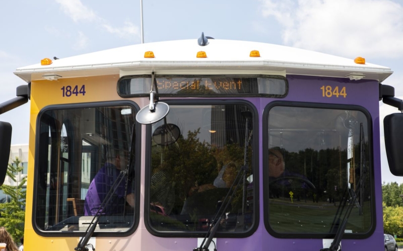 A closeup of the front and windshield of a purple and yellow bus with a marquee reading "Special Event"