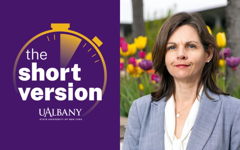 Composite image featuring a podcast logo on the left and a portrait of a woman with brown hair and a blue blazer posing in front of a bed of purples and yellow tulips on the right. The logo has a purple background with “The Short Version UAlbany” printed in white in the center of a gold stopwatch icon.  