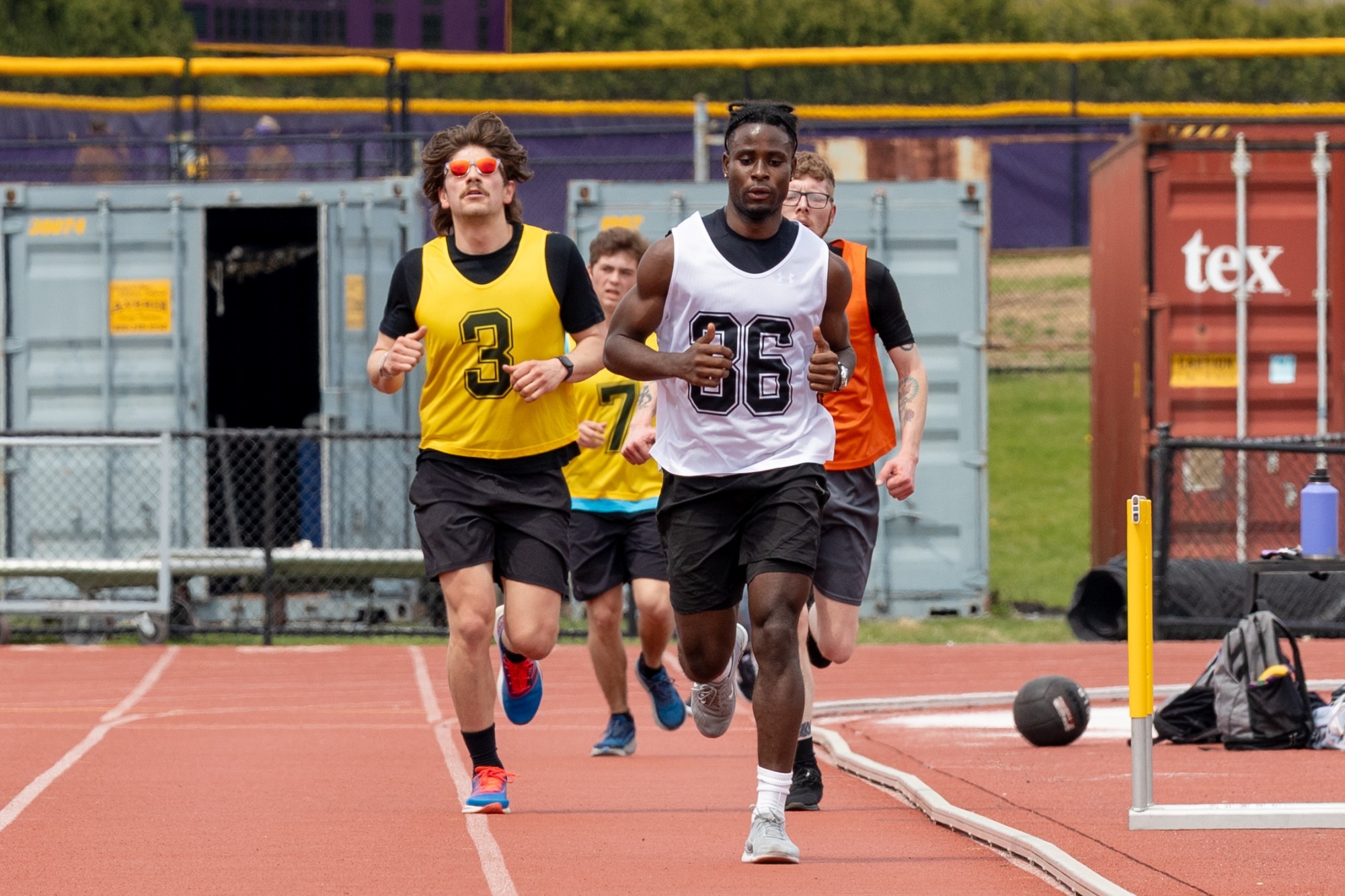 Students in white, yellow and orange jerseys run on the UAlbany track during the FBI physical fitness test.