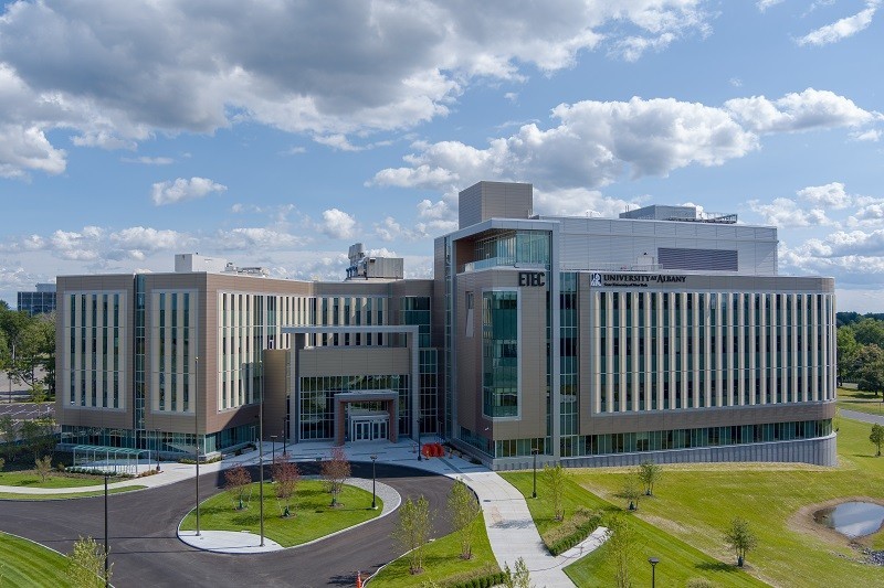 A exterior shot of a tan five-story science building surrounded by green lawns.