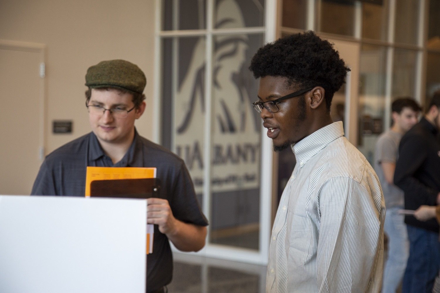 A student describes his poster to another student at the CEHC '22 Showcase