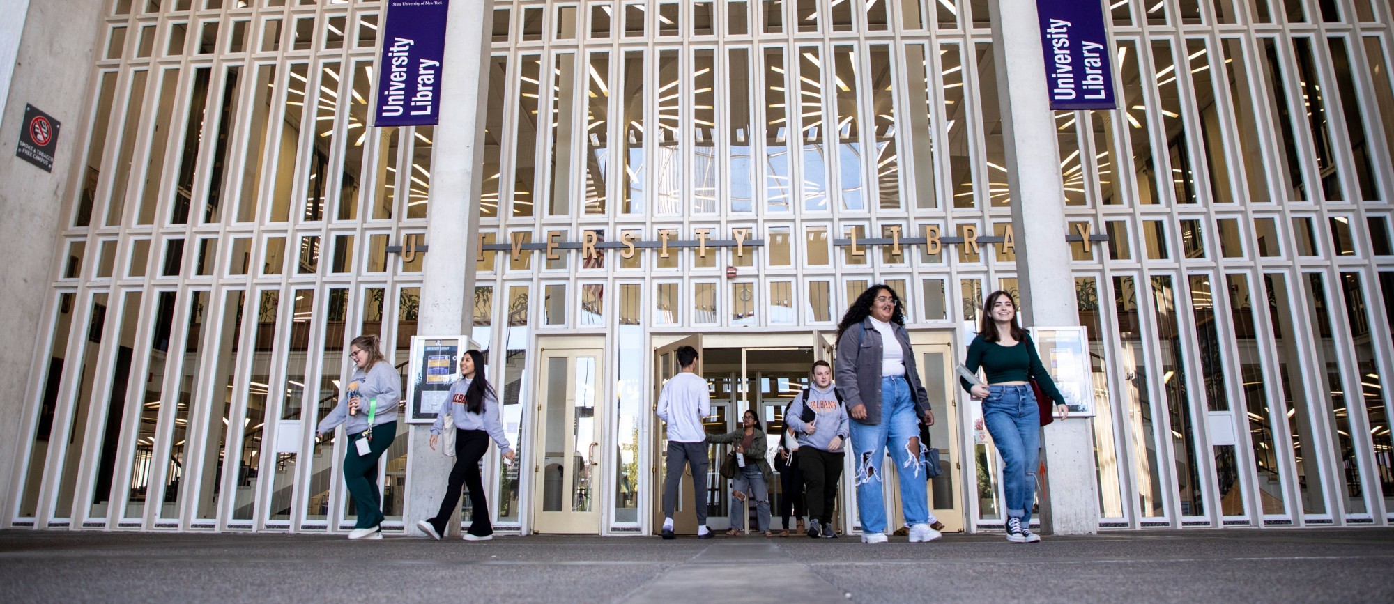 Students walk in and out of the University Library's main entrance.