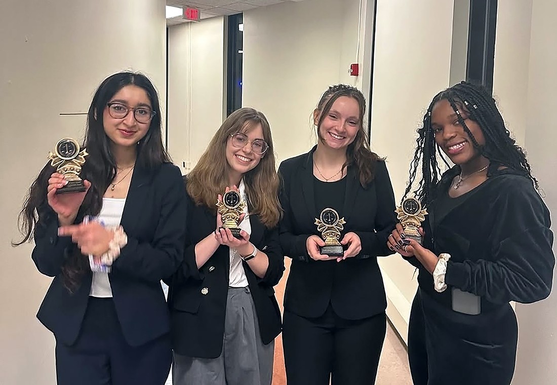 Four female college students hold awards as their picture is taken indoors