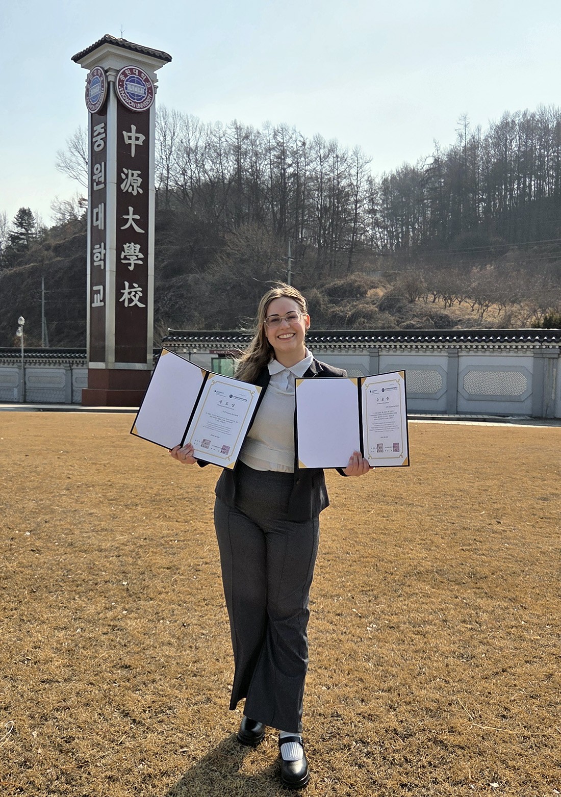 Kate Bucek stands in Korea with her awards from Fulbright for learning the Jeju dialect of Korean.