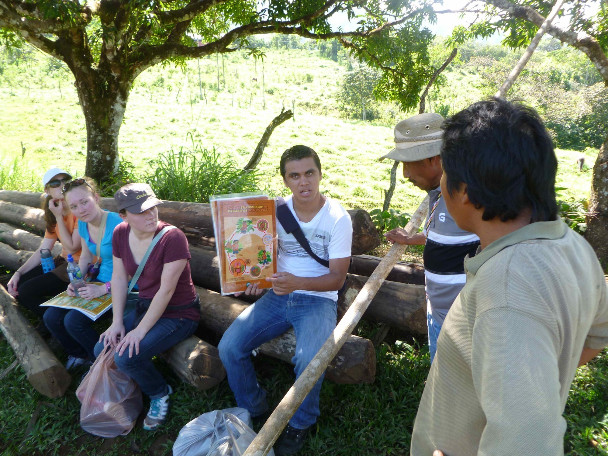 Jeancarlo sits on a bench in Costa Rica, holding a public health sign. 
