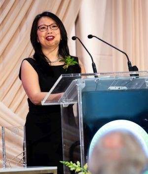 A smiling woman speaks at a lectern 