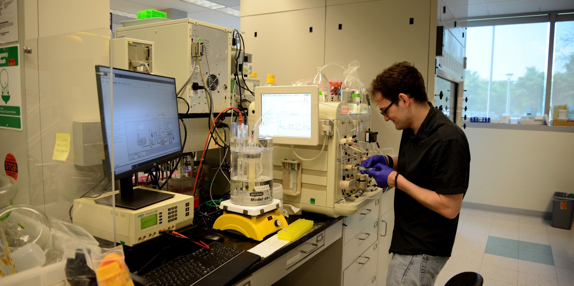 Another student researcher laughs as someone photographs him working inside the Niu Research Laboratory.