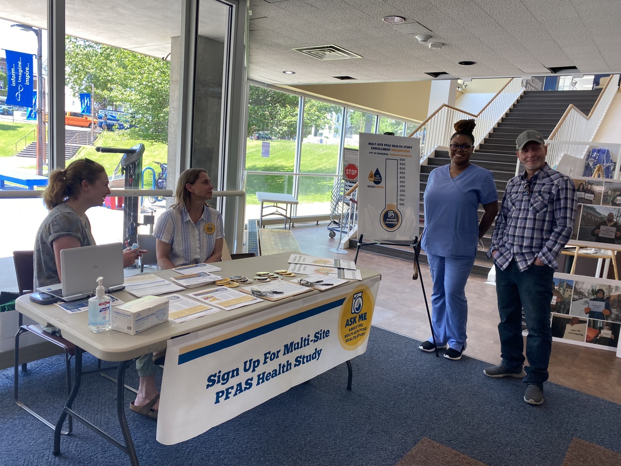 Researcher and Newburgh clinic staff stand at a table with flyers and other information to provide to local residents at the Newburgh Free Library. 