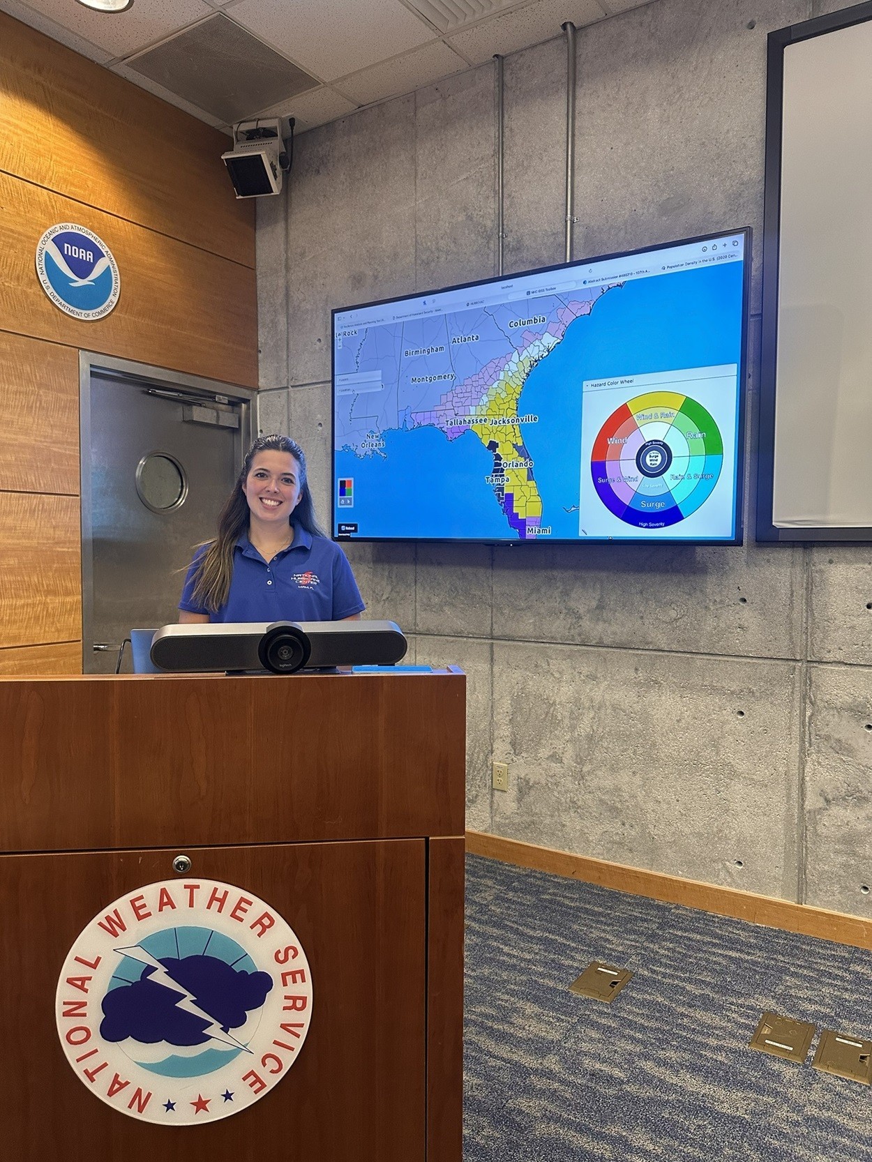 Micaela Maywald stands in front of a podium at the National Hurricane Center in Miami.