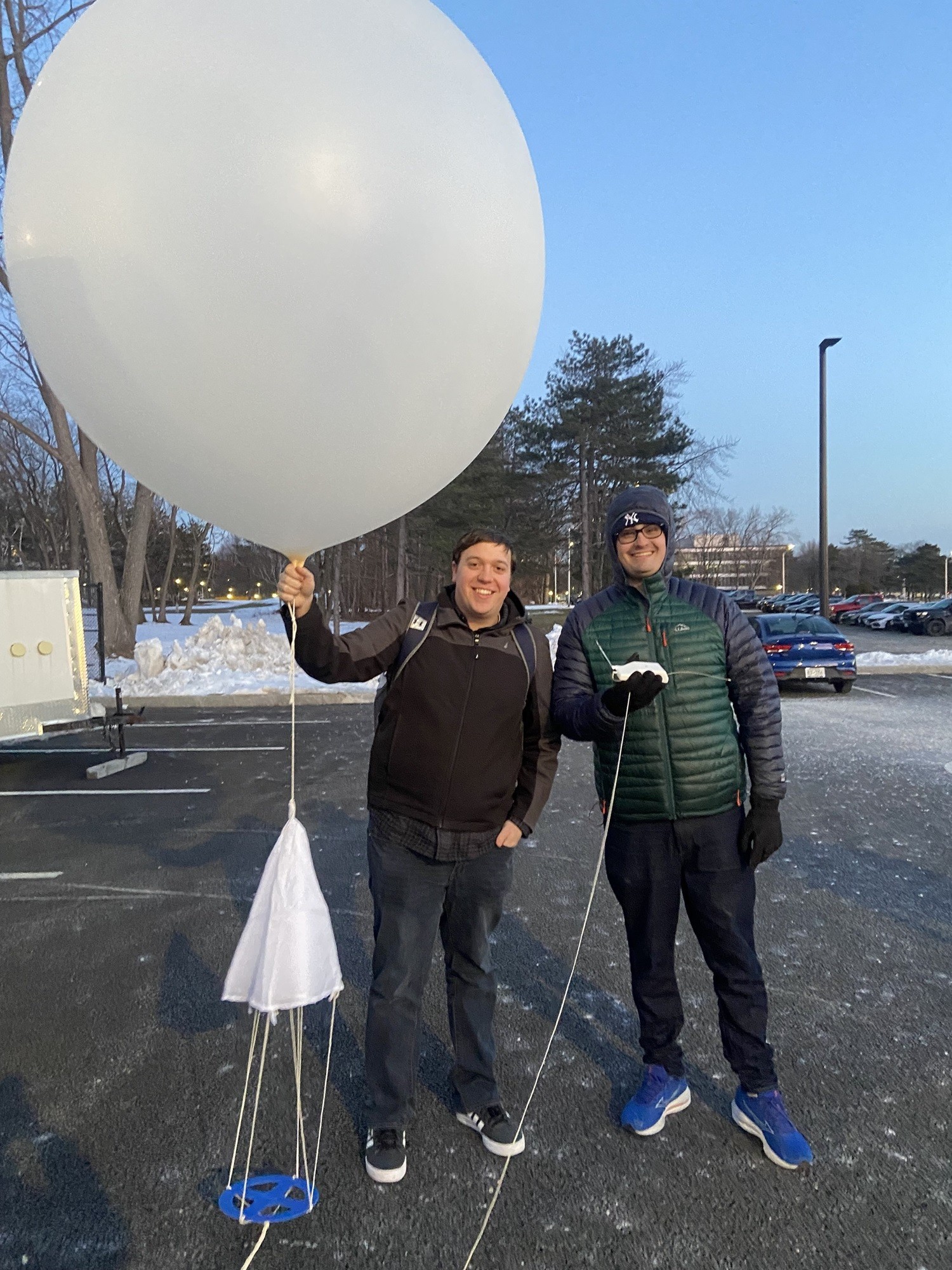 Two guys hold a weather balloon to prepare for launch in the ETEC parking lot.