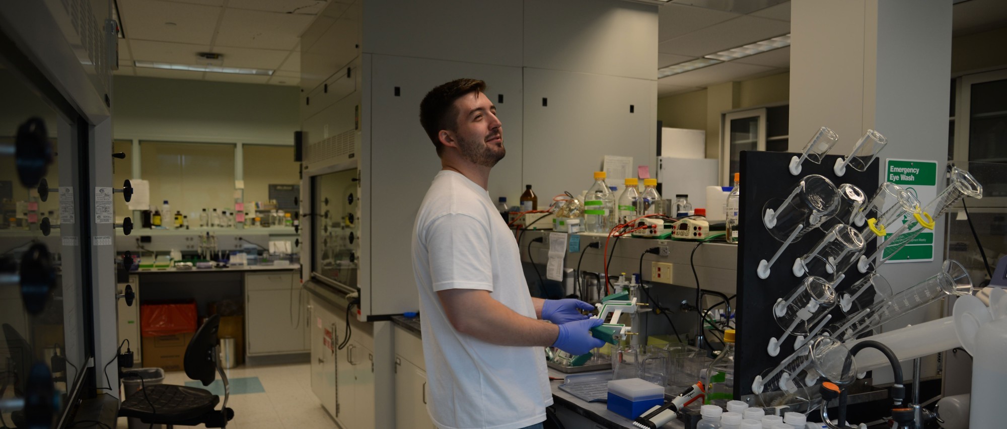 A student researcher laughs as someone photographs him working inside the Niu Research Laboratory.
