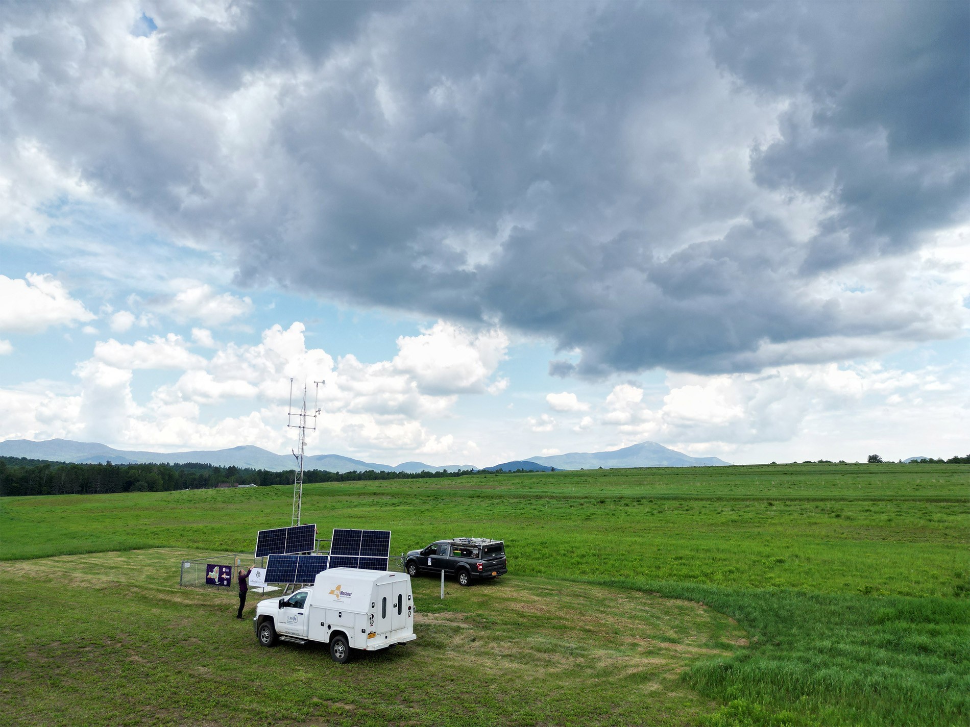 A drone image offers an ariel view of the Mesonet site in Lake Placid with the Adirondack Mountains behind it.