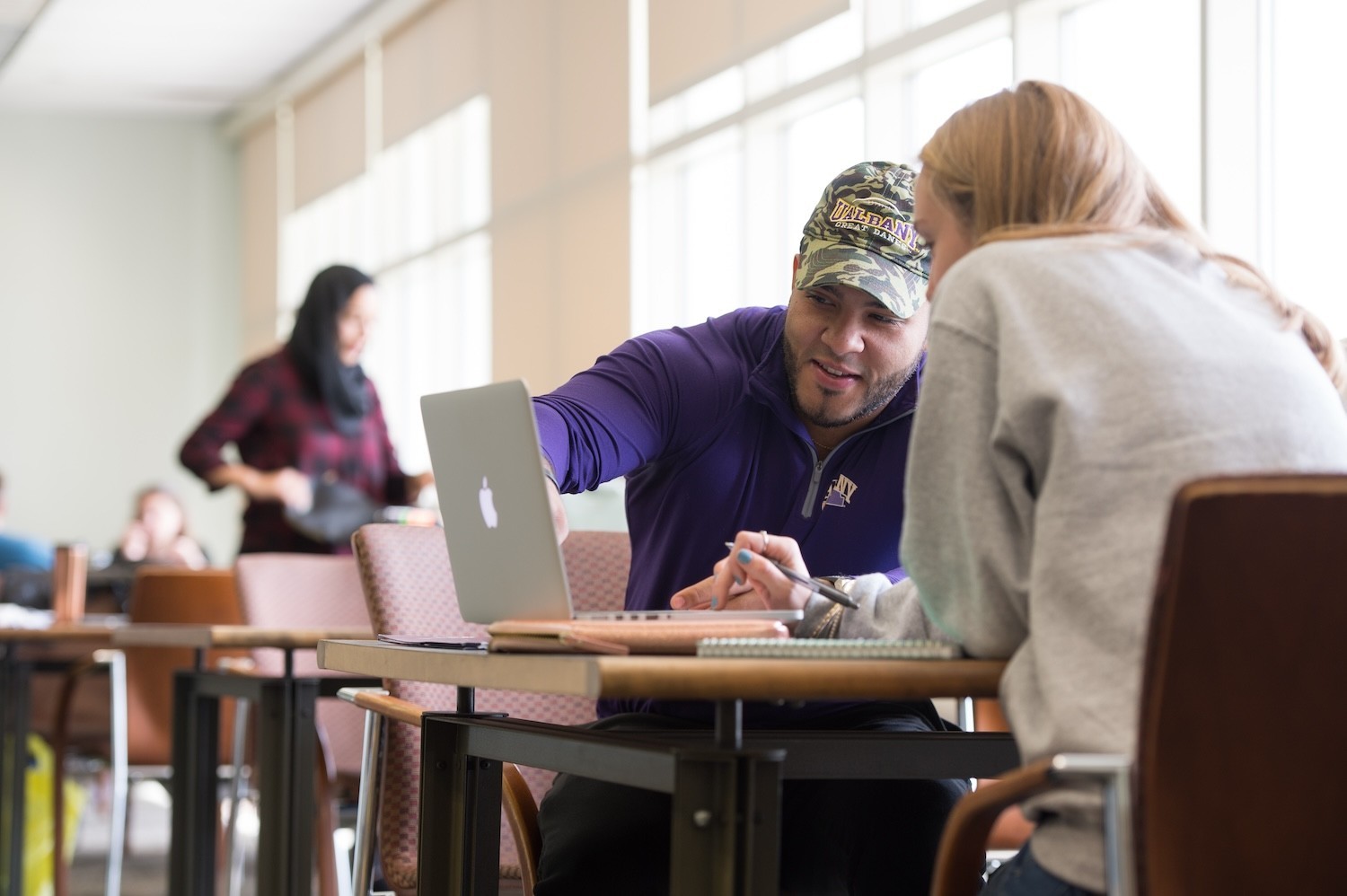 A student helping a peer student with an assignment on the computer