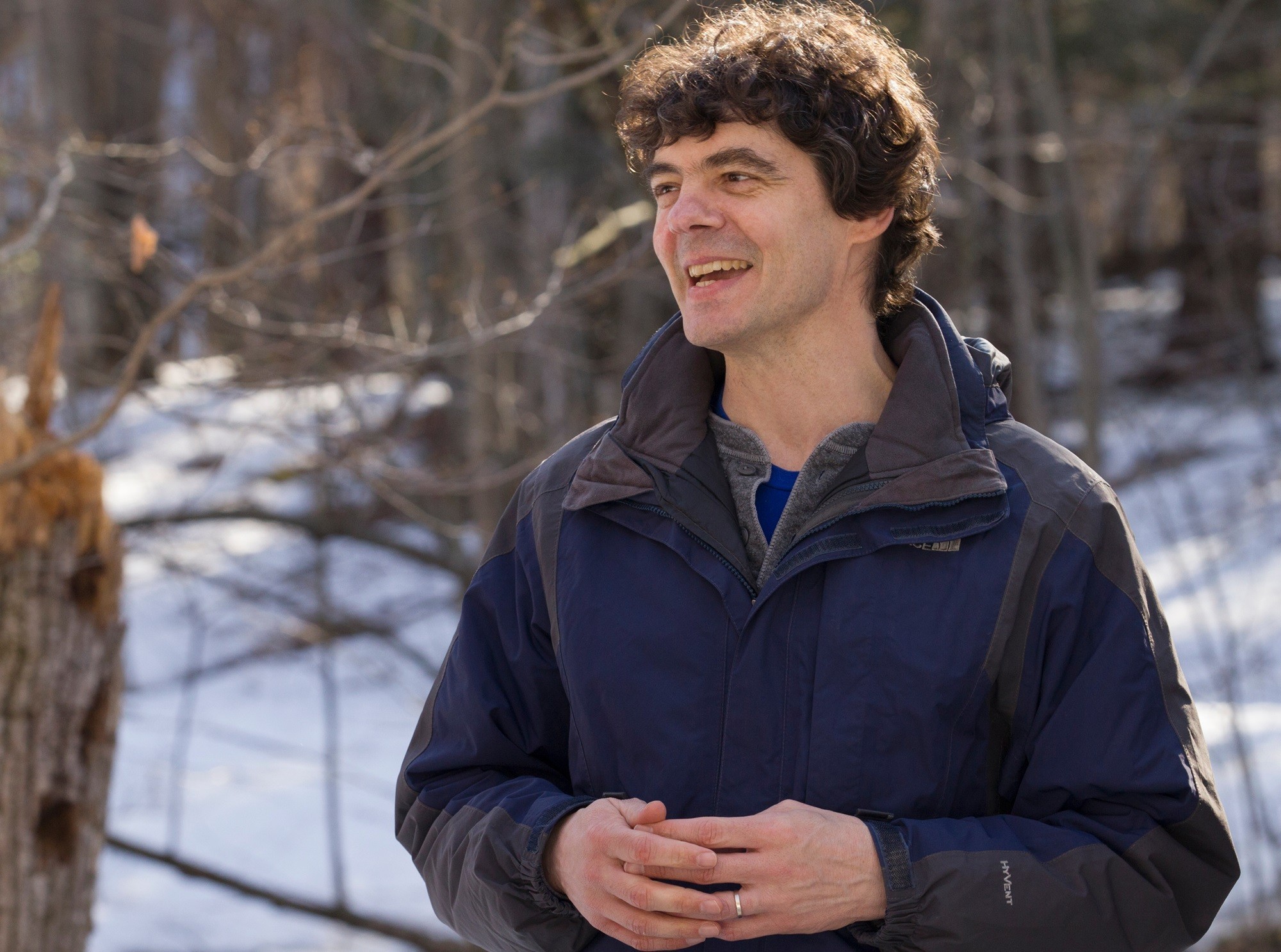 Mathias Vuille stands in front of a wooded area on campus in the winter season.