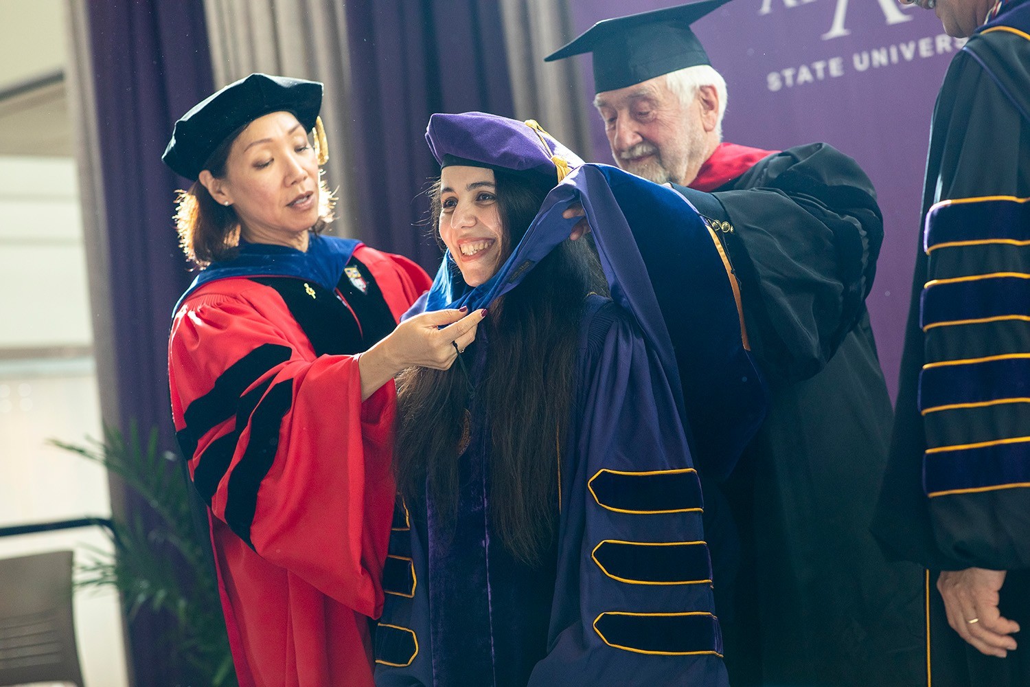 Najm on stage at the doctoral hooding with the Provost and her mentor.