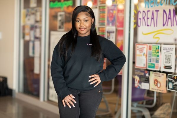 Nakisha Williams, dressed in black, stands in front of a window filled with posters