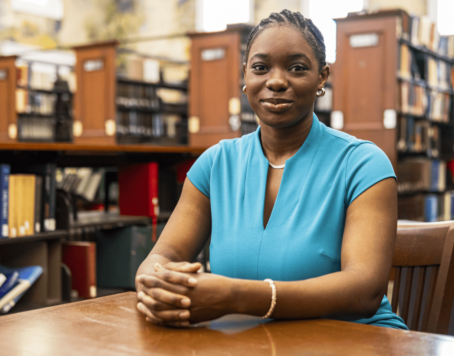 a woman in a blue shirt sits in a library
