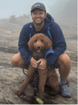A portrait of Phil with his brown dog in front of him.