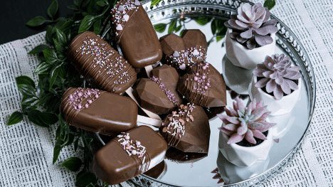 Chocolate candies sit on a reflective plate.