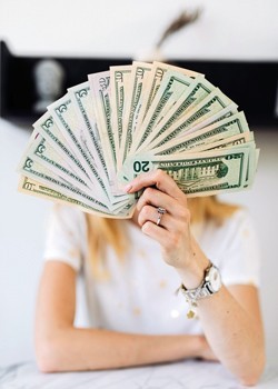 A person holding out a fan of U.S. paper money.