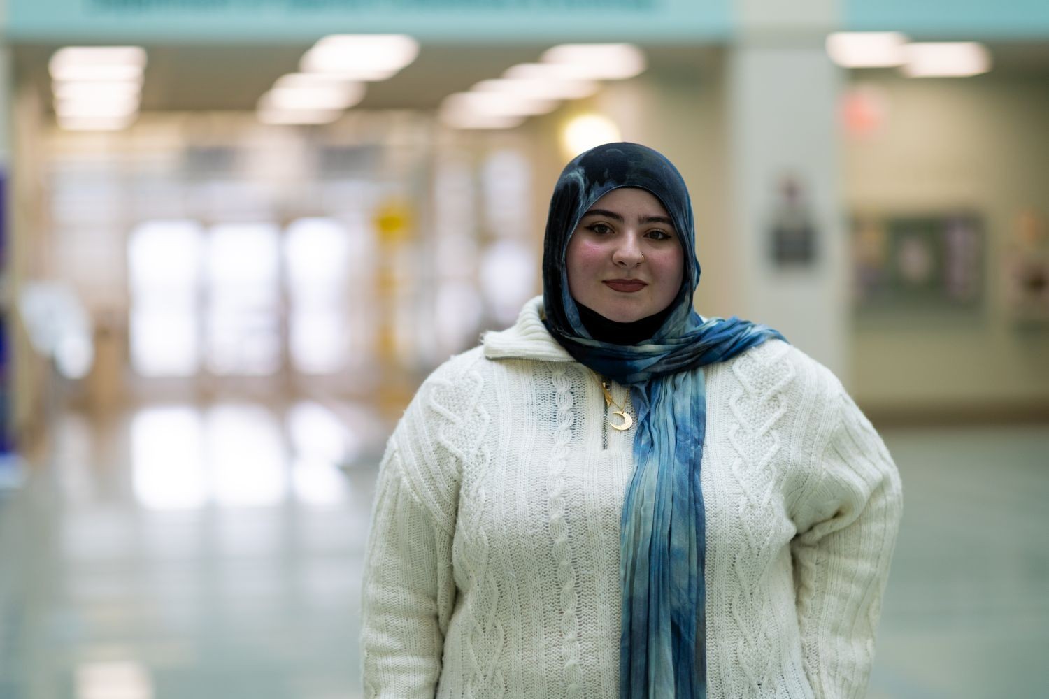A woman in a white sweater and blue head scarf