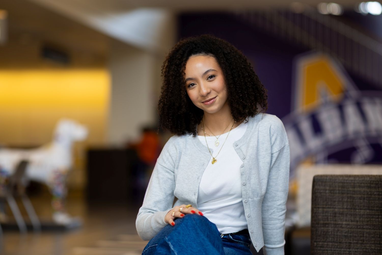 a curly-headed woman in a white T-shirt and gray sweater