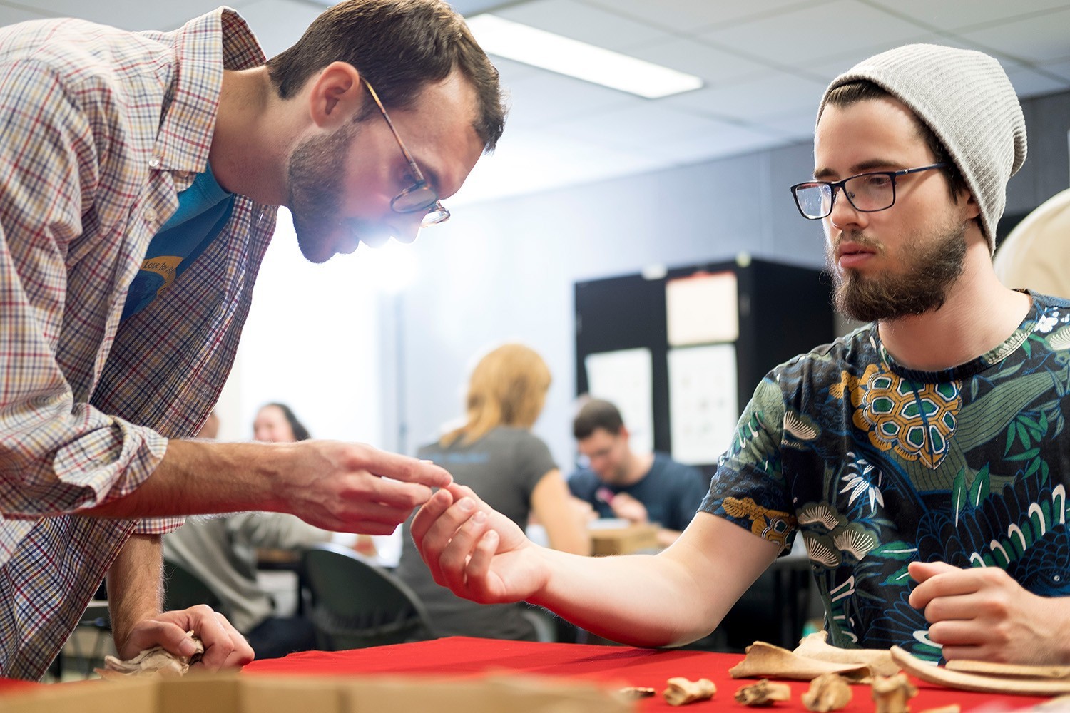 A teaching assistant works with a student in an Archaeology lab class.