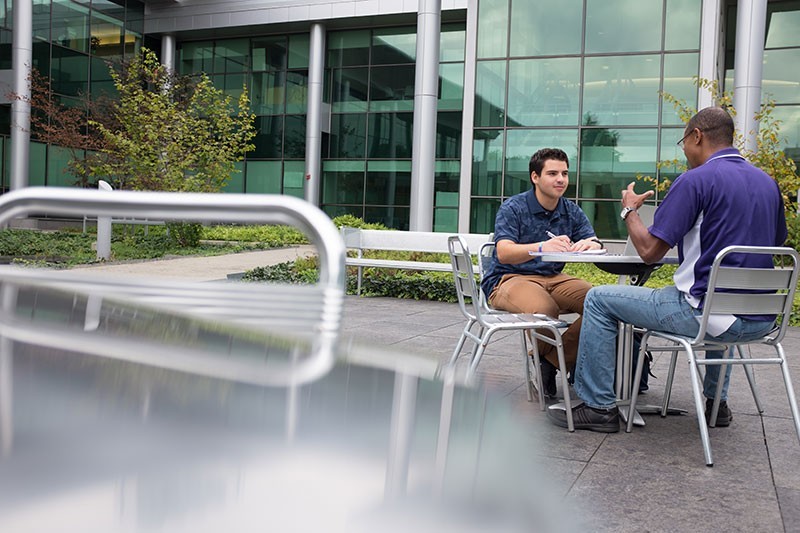 Professor and student having a conversation on campus.