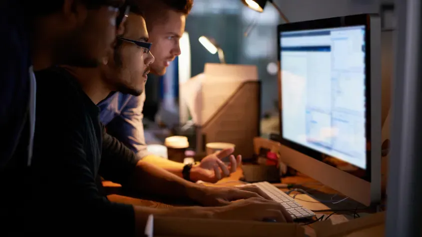 Three young professionals working on a computer